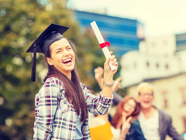 Smiling teenage girl in corner-cap with diploma