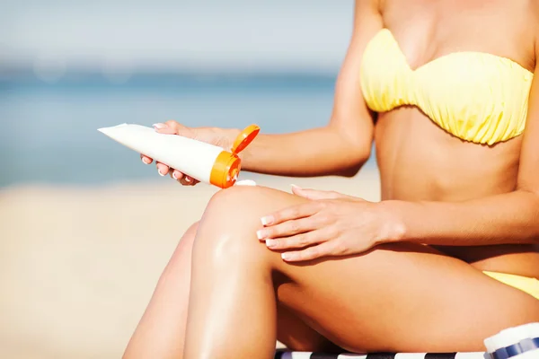 Girl putting sun protection cream on beach chair