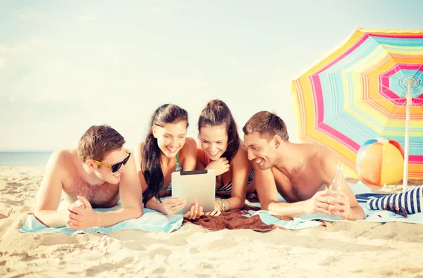 Group of smiling people with tablet pc on beach