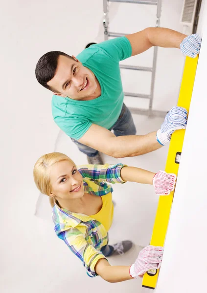 Couple building using spirit level to measure