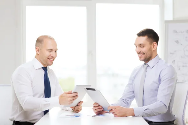 Two smiling businessmen with tablet pc in office