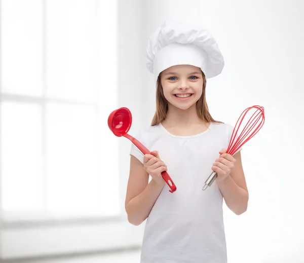 Smiling girl in cook hat with ladle and whisk