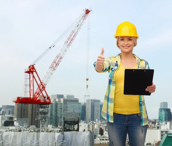 Smiling woman in helmet with clipboard