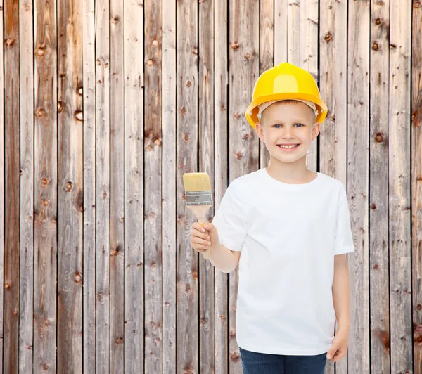 Smiling little boy in helmet with paint brush