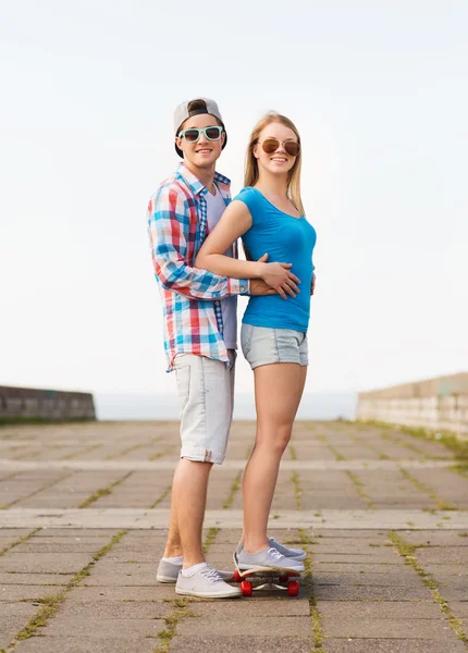 Smiling couple with skateboard outdoors