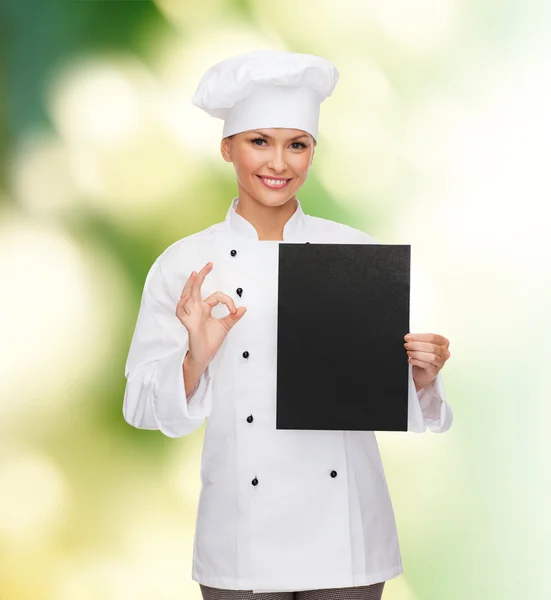 Smiling female chef with black blank paper