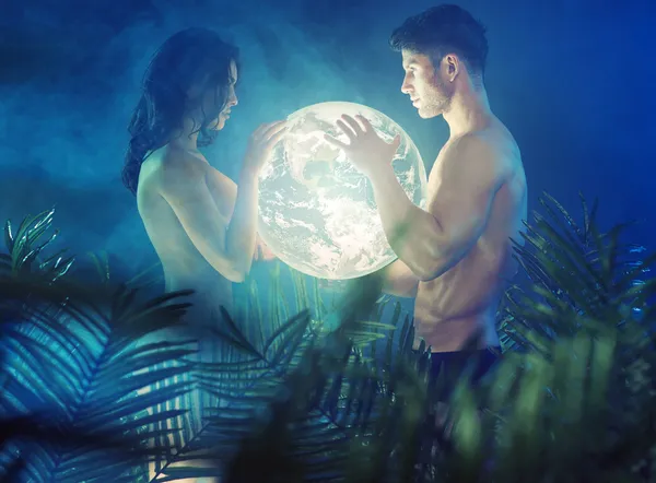 Naked couple holding shiny Earth