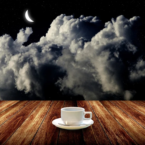 Hot coffee on wooden table with night sky
