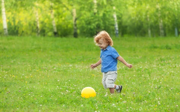 Little boy kicking yellow ball