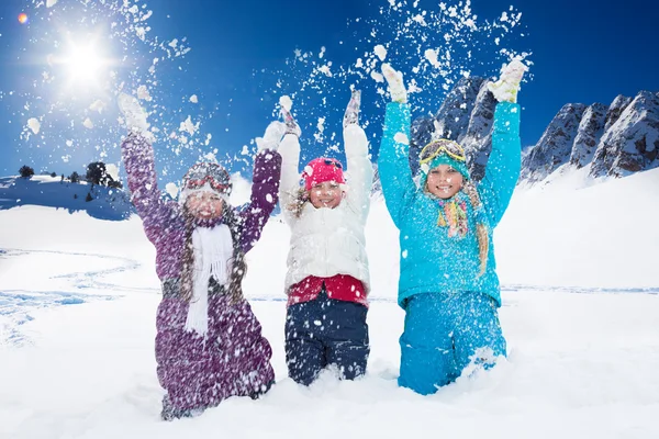 Three happy girls having fun with snow