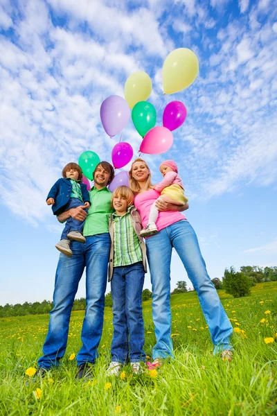 Parents and kids stand with balloons in park