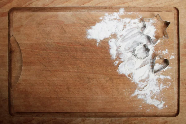 The form for cookies on the wooden board poured by a flour
