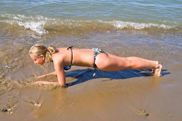 Girl holds her elbows on the bar. Fitness on beach