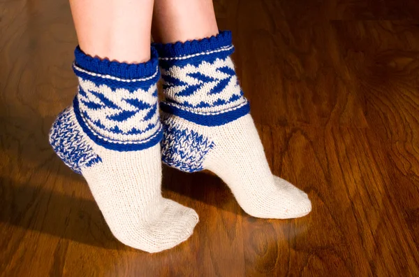 Feet warm socks on dark wooden floor