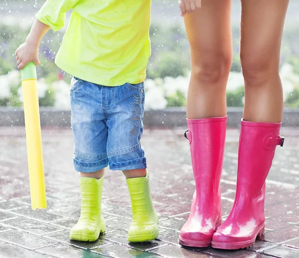Child and mother wearing pink and green rain boots