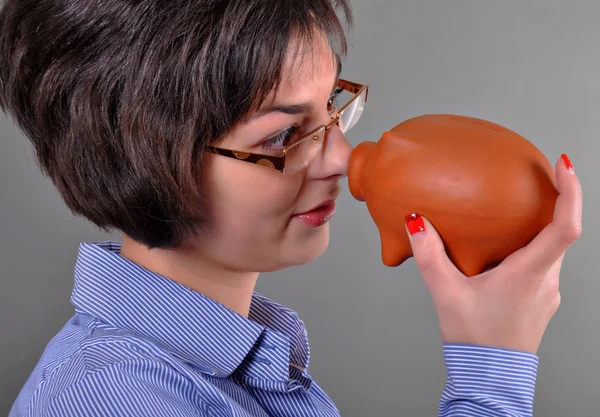 Young woman trying to get money from her piggy bank