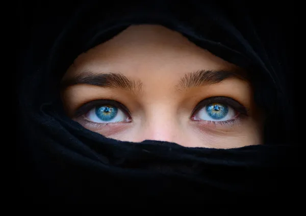 Beautiful blue woman eyes behind black scarf looking up