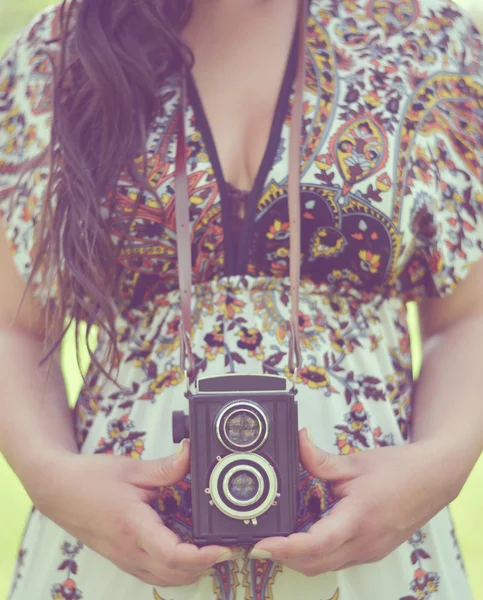 Retro image of woman hands holding vintage camera outdoors