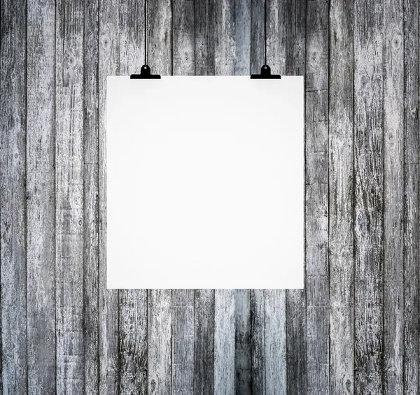 Blank paper board hanging on grunge wooden wall