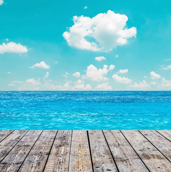 Blue ocean and sky above wooden floor