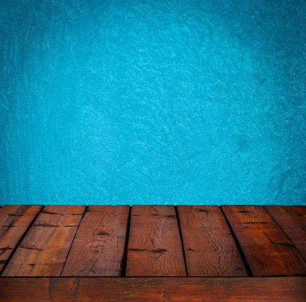 Background with wooden table and grunge blue wall