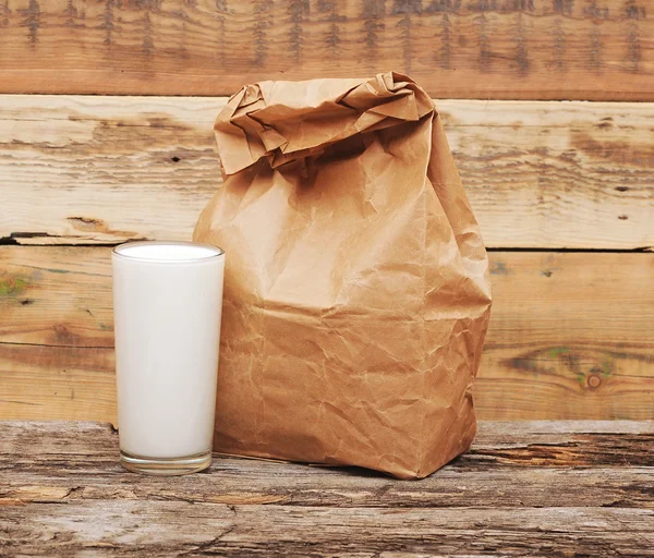 Paper lunch bags with glass milk over wooden background