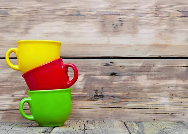 Colorful cups on the wooden background