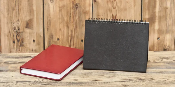 Desk calendar with red leather note book on wood table