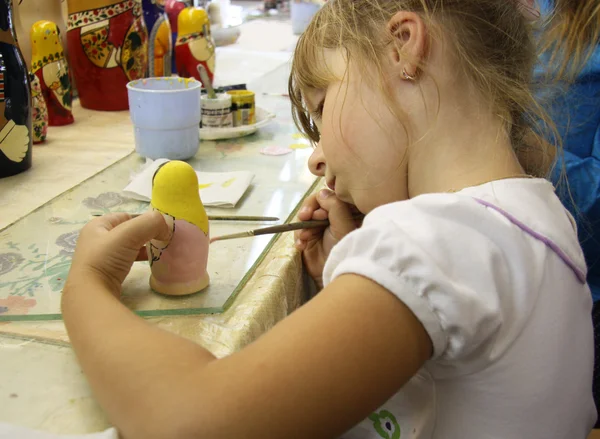 Little girl painting a matrioshka russian doll