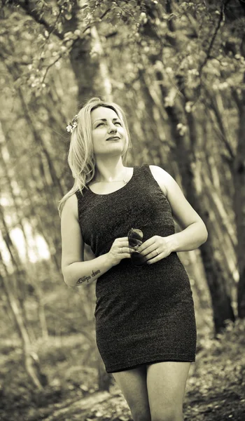 Portrait of a beautiful girl on the nature, in the woods, in a black dress. Sepia toned photo