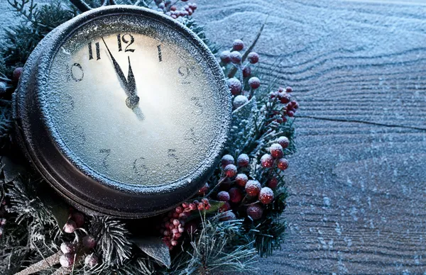 Christmas clock over snow wooden background.