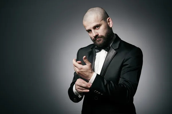 Stylish and brutal bald man with a beard  in elegant black suit