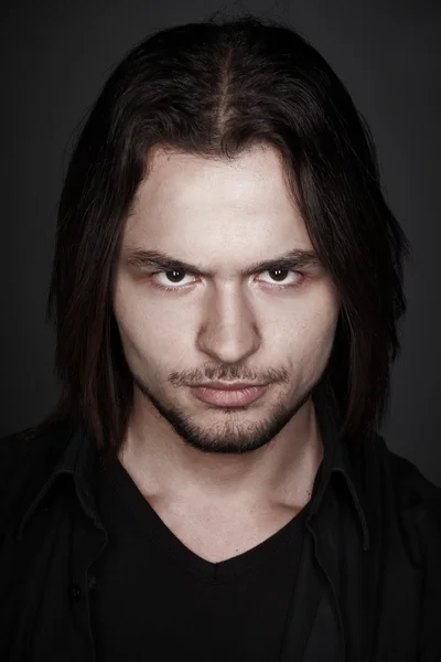 Closeup portrait of a stylish young man with long hair, studio shoot