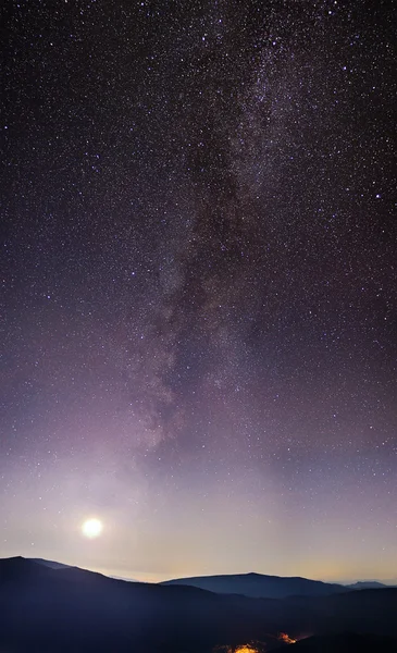 Part of a night sky with stars and Milky Way on with mountains b