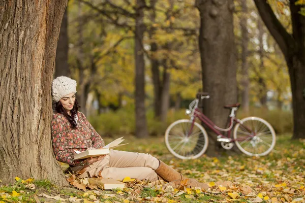 Young woman reading in the autumn forest