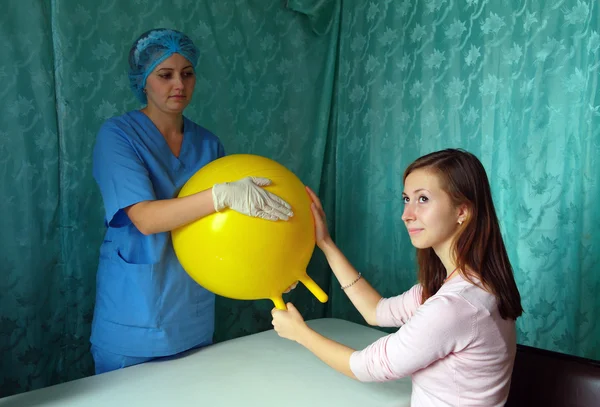 Physician and patient in their hands massaging yellow inflatable ball