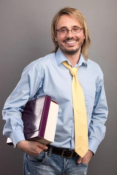 Portrait of handsome young man holding a folder and a book against grey background