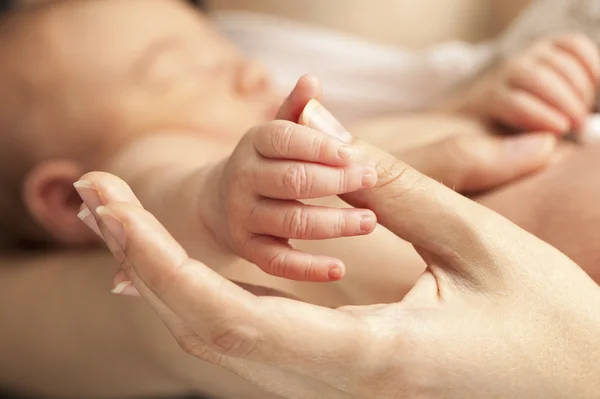 Closeup view of newborn\'s hand holding mother\'s thumb, image with shallow depth of field