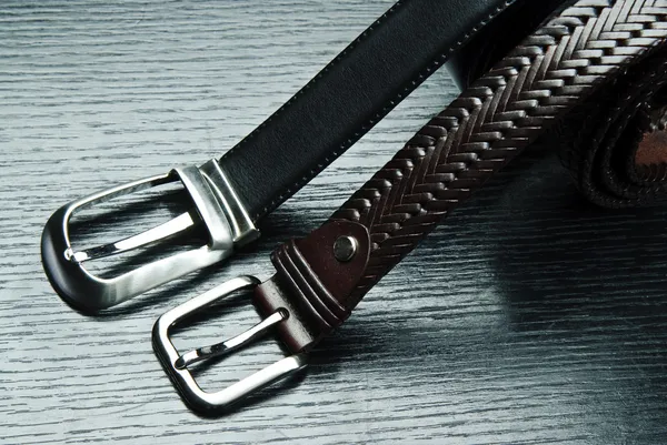 Two men\'s belts on grey background