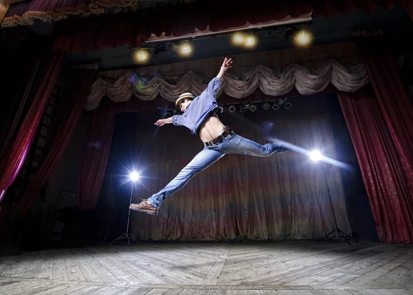 Modern ballet style male dancer performs on high lighted stage