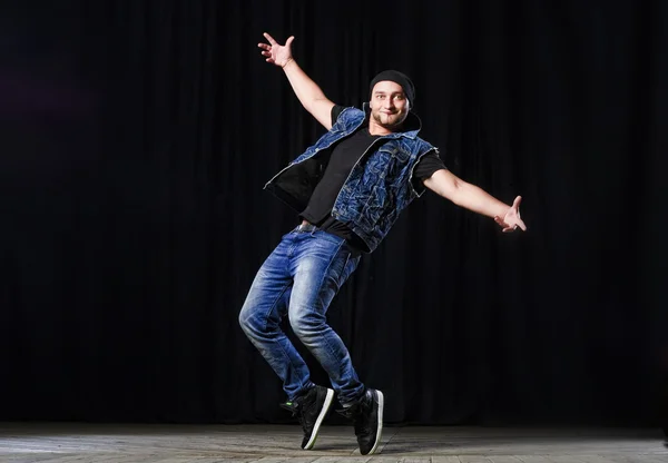 Stylish hip-hop male dancer performs on the stage on black background