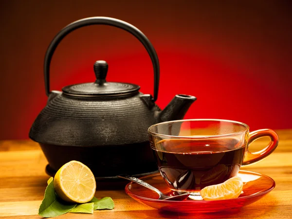 A cup of black tea with teapot in the background