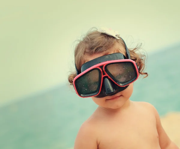 Happy child girl in diving mask smiling on beach background. Vin