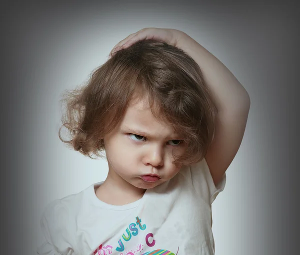 Angry kid on grey background. Closeup portrait