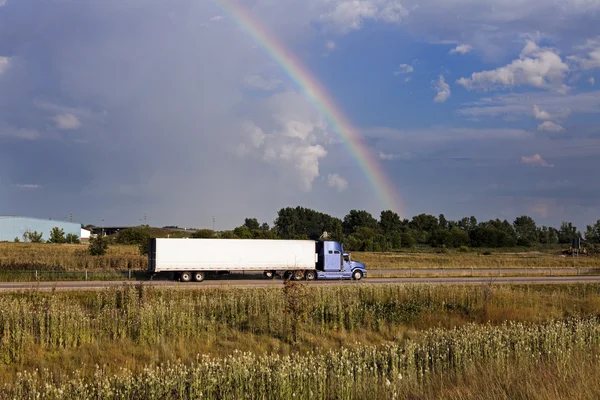 Semi truck driving under the rainbow