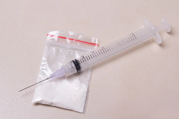 Drug syringe and heroin powder in pack on the floor