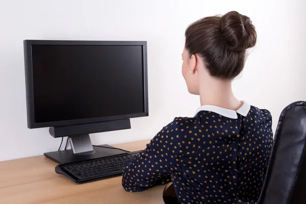 Back view of young beautiful business woman using pc with empty