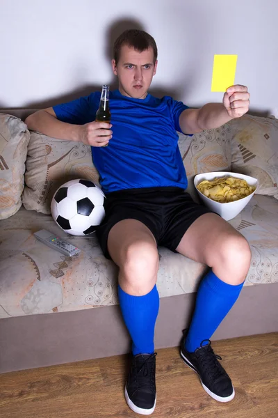 Supporter watching football on tv at home and showing yellow car