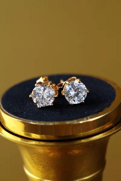 Gold earrings stud with diamonds on gold background