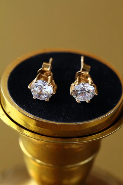 Gold earrings stud with diamonds on gold background